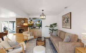 A spacious living room with a fireplace, comfortable seating, and a large TV. - Spacious 6-bedroom house with fitness room and AC in charming Buena Park (Buena Park)
