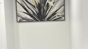 Une chambre avec un lit superposé et un tableau abstrait encadré accroché au mur.