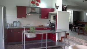 A modern kitchen with red cabinets, stainless steel appliances, and a central island.