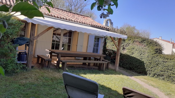 A rustic wooden building with a tiled roof, a picnic table, and benches.