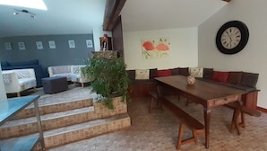A dining area with a wooden table and benches, a clock on the wall, and a staircase leading to another room.