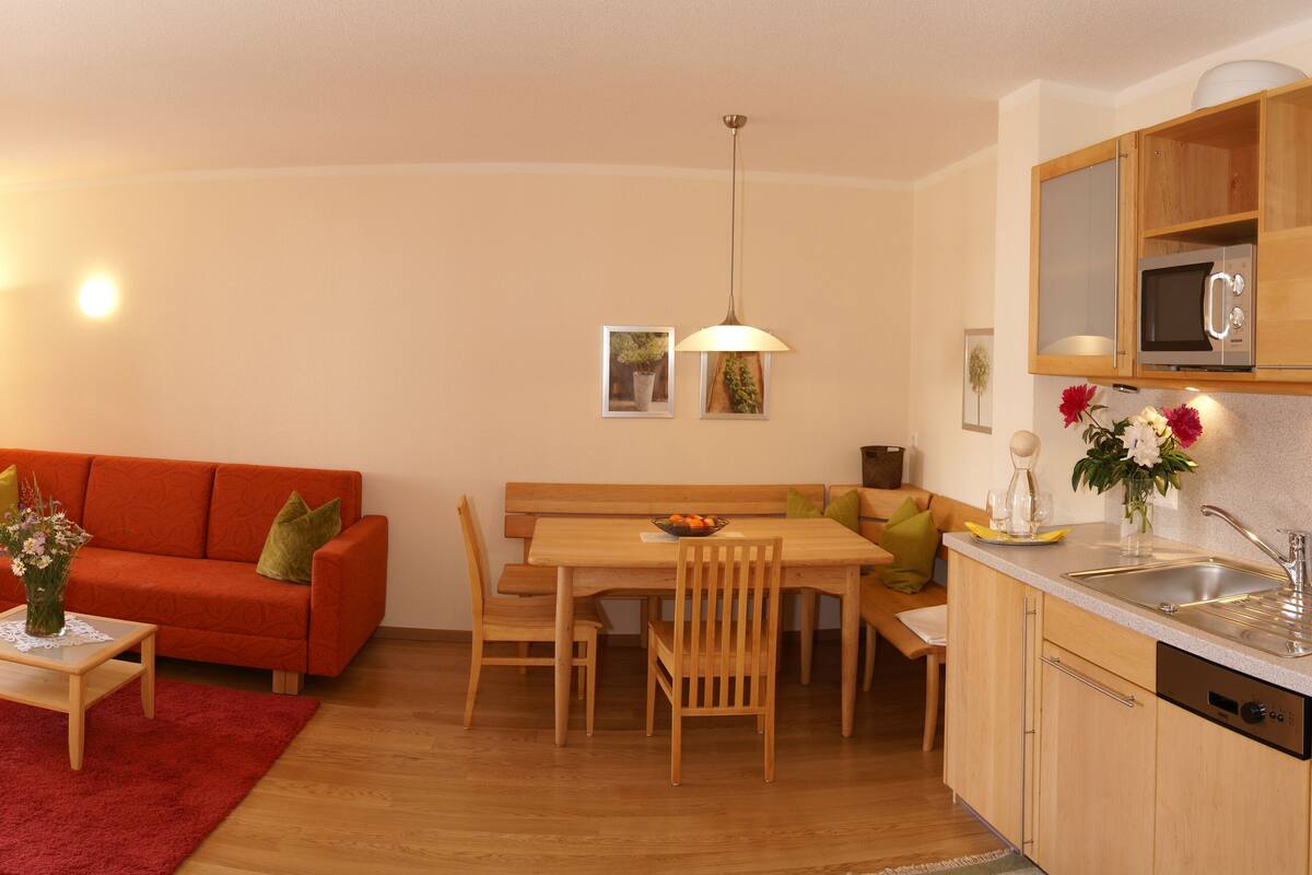 A compact living space with a sofa, dining table, and kitchenette.