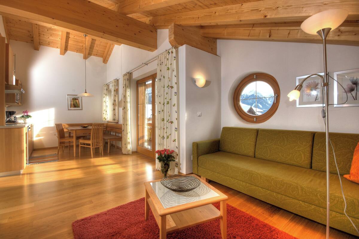 A cozy living area with a sofa, a dining table, and a kitchen in the background.