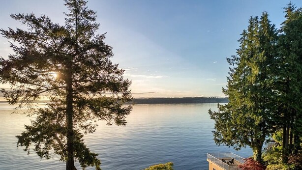 Une propriété située au bord d’un lac, dotée d’une terrasse offrant une vue sur l’eau, et entourée d’une végétation luxuriante et d’arbres.