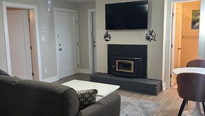 Un salon avec un canapé, une cheminée, un téléviseur et un ventilateur de plafond.