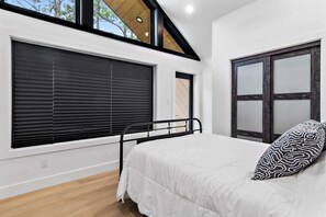 A bedroom with a bed, a window with blinds, and a view of the outdoors. - Modern Glass-Front Retreat l Stunning Nature Views (Santa Rosa Beach)