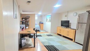 Eine kleine Küche mit Essbereich, Holzschränken, einem Kühlschrank und einem Fernseher.