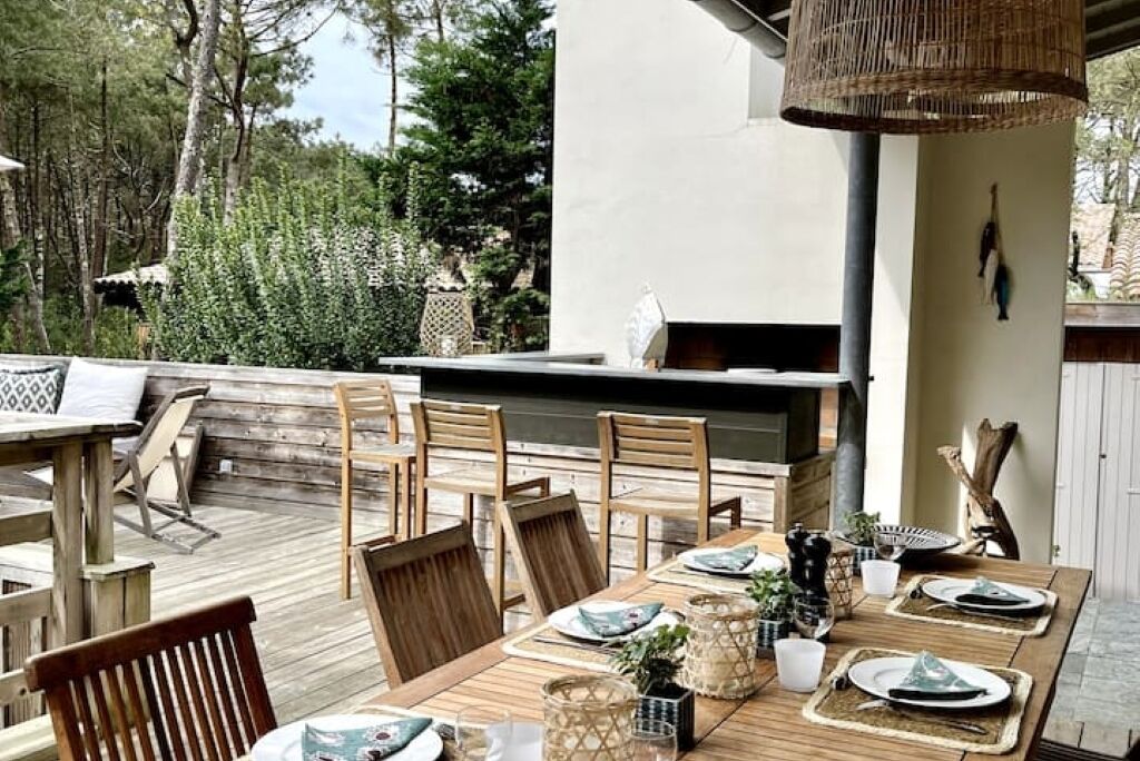 Een terras met houten meubels en een tafel gedekt voor vier personen.