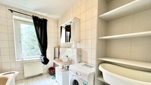 A compact, well-lit bathroom with a washing machine, a sink, and a mirror. - Modern apartment for sale in Chemnitz (Chemnitz)