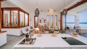 Un'ampia cucina con un'isola grande, mobili in legno e vista sull'oceano.
