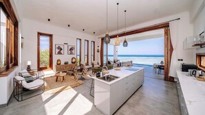 Un ampio soggiorno con cucina a isola, arredi in legno e vista mare.