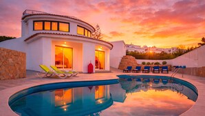 A modern villa with a swimming pool, outdoor seating, and a sunset view. - Renovated Villa with Heatable Saltwater Pool (Carvoeiro)