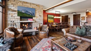 Una sala acogedora con chimenea de piedra, muebles de cuero y un comedor.