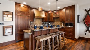Una cocina con gabinetes de madera, encimeras de granito y taburetes de bar.
