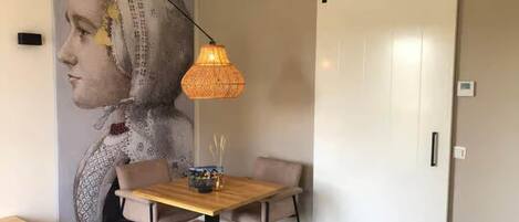 Een eetruimte met een tafel, stoelen, een wandlamp en een schuifdeur.
