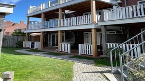 Un immeuble résidentiel à deux étages, doté d’un balcon à chaque étage, d’un porche couvert et d’une allée pavée.