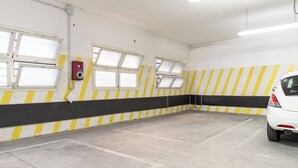 Ett parkeringsgarage med gul- och svartrandiga väggar, flera fönster och en vit bil som står parkerad en bit bort.