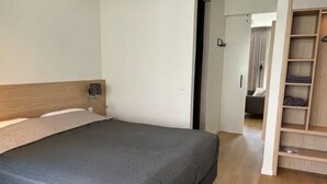 A bedroom with a large bed, a wooden headboard, a bedside table, and a built-in wardrobe. - Lavish Lodge With Private Sauna (Zoutelande)