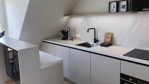 Uma cozinha moderna com uma pia embutida, uma torneira preta e uma bancada. Há armários abaixo da bancada e uma pequena prateleira acima da pia.