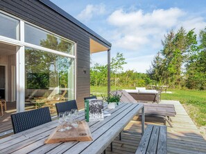 Une terrasse extérieure avec des meubles en bois, un livre intitulé « 1864 » et une table en verre.