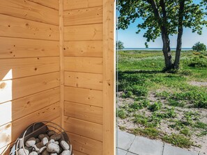 Uma sauna de madeira com vista para a praia e árvores.