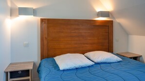 A bedroom with a wooden headboard, two bedside tables, a bed with blue bedding, and wall-mounted lights. - T. de Pentrez Ndeg75 - 2P4 (Saint-Nic)