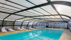 An indoor swimming pool with a glass ceiling, white lounge chairs, and a clear view of the sky. - T. de Pentrez Ndeg75 - 2P4 (Saint-Nic)