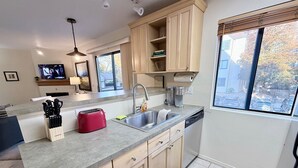 Une cuisine moderne avec des meubles en bois, un évier en acier inoxydable et un lave-vaisselle encastré.