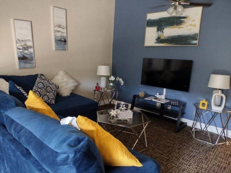 Un salon avec un canapé bleu, une table basse, un téléviseur et un ventilateur de plafond.