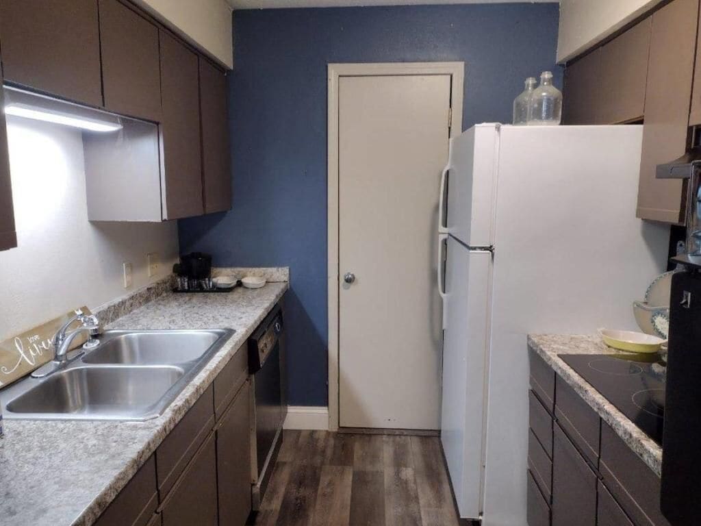 A compact kitchen with a white refrigerator, a double sink, and wooden cabinets.