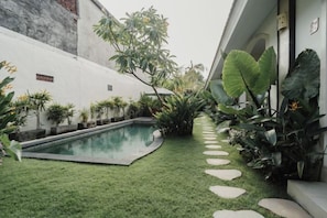 A pool surrounded by a well-maintained lawn and various plants. - D'Leafy Seminyak (Bali)