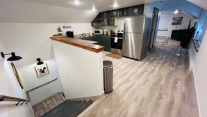 Una cocina moderna con una isla de madera, electrodomésticos de acero inoxidable y una escalera que lleva a otro nivel.