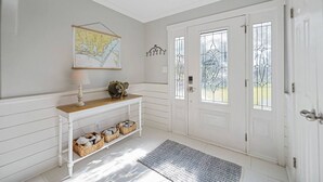 A hallway with a white console table, a map, and a decorative door with stained glass. - Hot Tub~Waterfront Retreat~EPIC Game Room~Private (Beaufort)