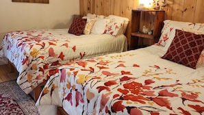 Una habitación con dos camas, un cabecero de madera, un cuadro en la pared y una mesita de noche con una lámpara.