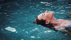 Una persona flotando en una piscina azul cristalina.