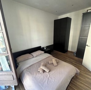 Ein Schlafzimmer mit Bett, Nachttisch, Kleiderschrank und einer Tür.