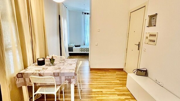 Moderni, hyvin valaistu huone, jossa on puulattia, kahdelle katettu ruokapöytä ja penkki.