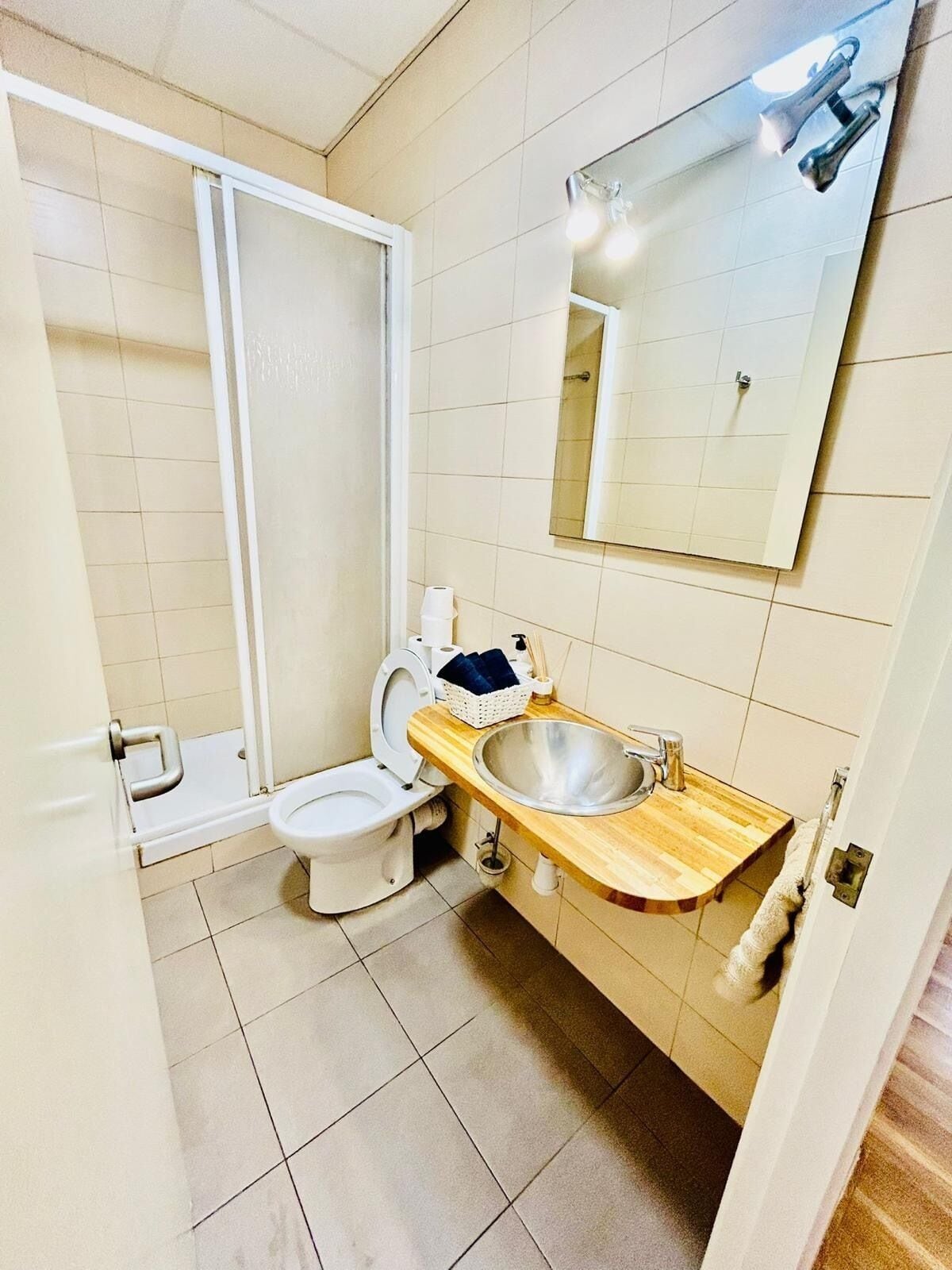 A bathroom with a toilet, a sink, a mirror, and a shower.