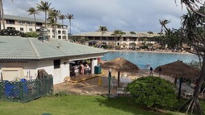 Un resort con piscina, area salotto all'aperto e palme.