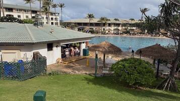 A resort with a swimming pool, outdoor seating, and palm trees.