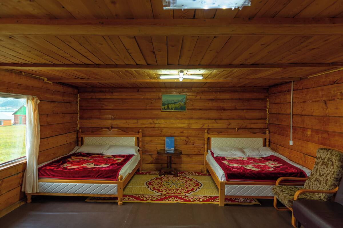 A cabin with two wooden beds, a small table, and a chair.