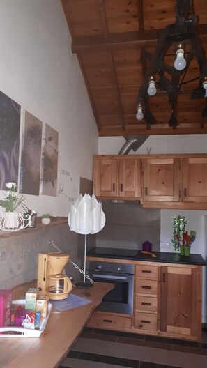 A kitchen with wooden cabinets, a coffee maker, and a hanging light fixture.