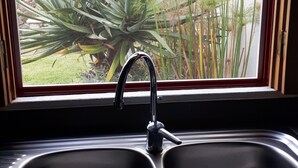 Een keuken met een dubbele spoelbak en een raam met uitzicht op een tuin.