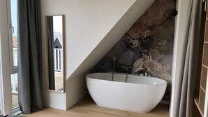 A modern bathroom with a freestanding bathtub, a mirror, and a view of the outside. - Lodge With a Magnificent View of the Dunes (Zoutelande)
