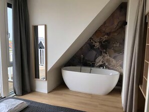A modern bathroom with a freestanding bathtub, a mirror, and a view of the outside. - Lodge With a Magnificent View of the Dunes (Zoutelande)