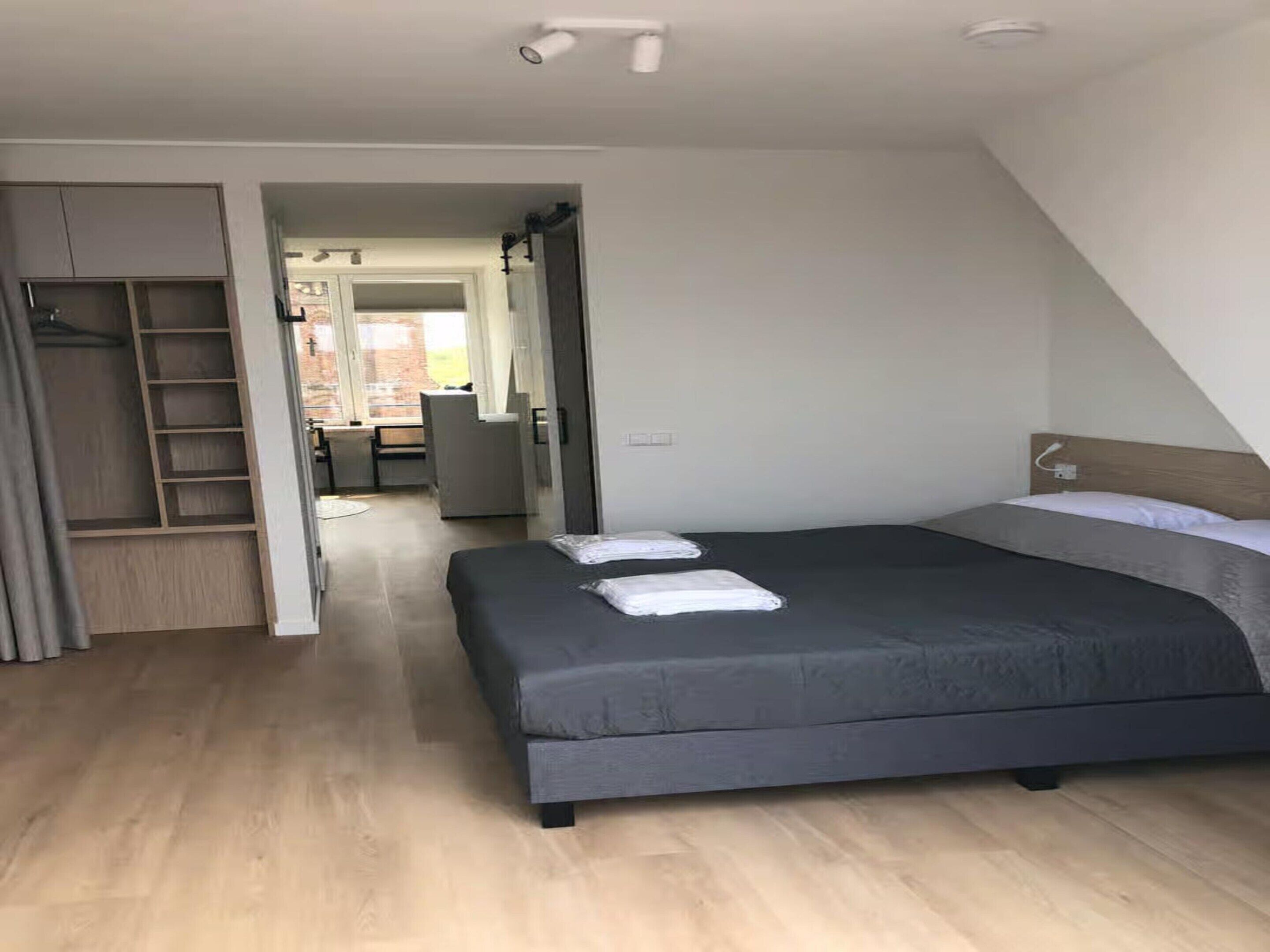 Une chambre avec un grand lit, une armoire et un espace bureau.