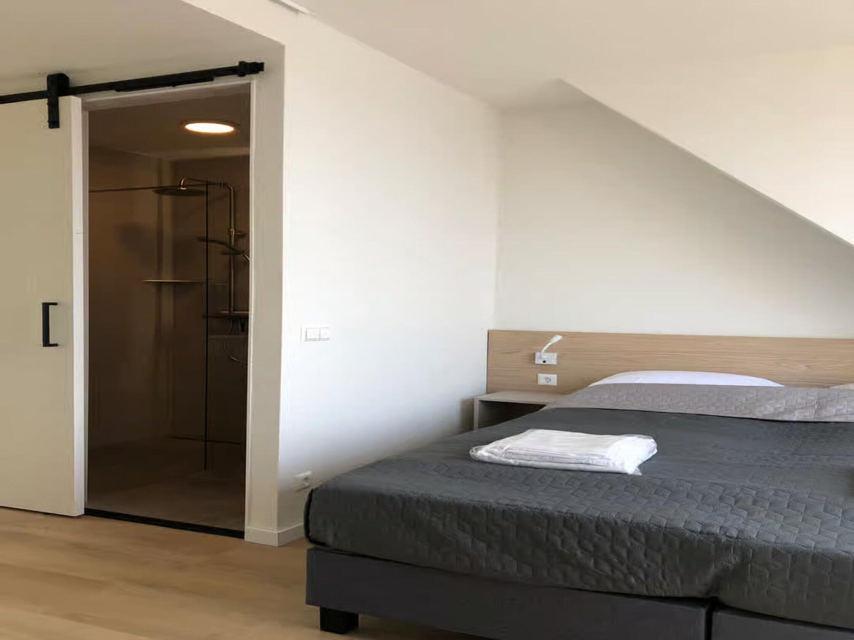 Une chambre à coucher moderne avec un lit, une table de chevet et un dressing.
