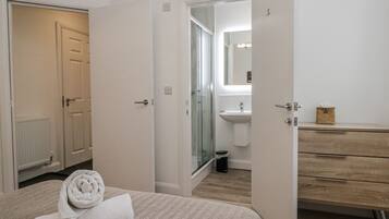 A bedroom with a bed, a bathroom with a sink and toilet, and a wooden dresser.