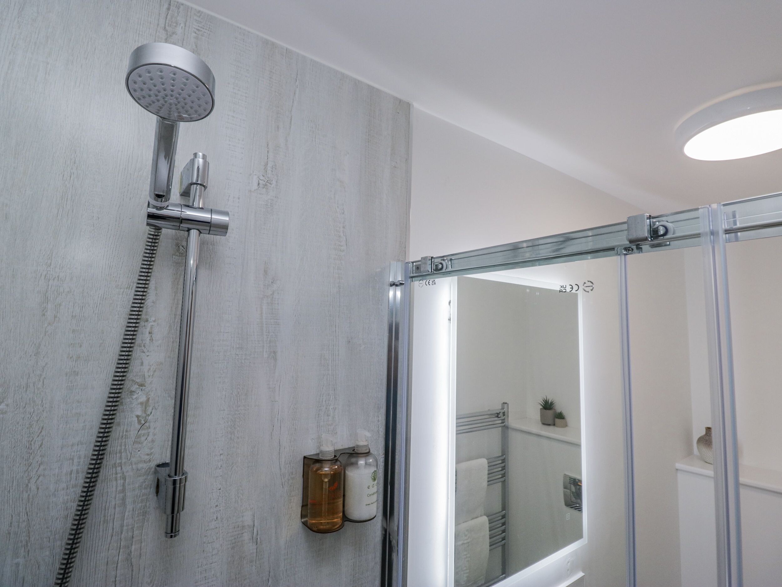 A modern shower with a glass enclosure, a handheld showerhead, and a flexible hose.