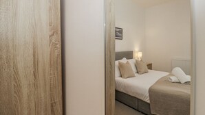 Un dormitorio con cama, lámparas de noche y vista a través de una puerta.